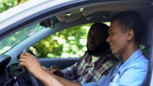 father teaching teenage son how to drive safely