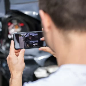 a man taking a picture of his car after an accident
